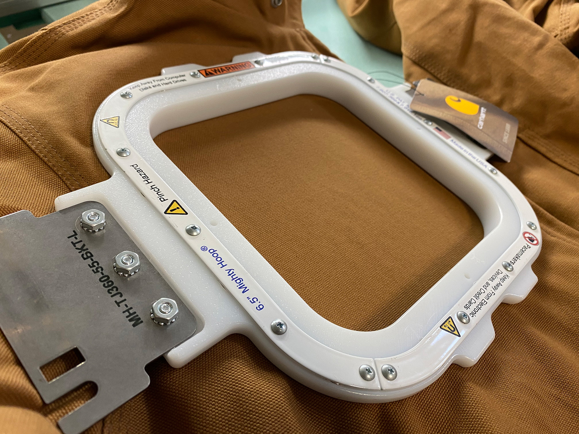 Wide shot of a Carhartt jacket hooped with the magnetic clamp on the embroidery machine